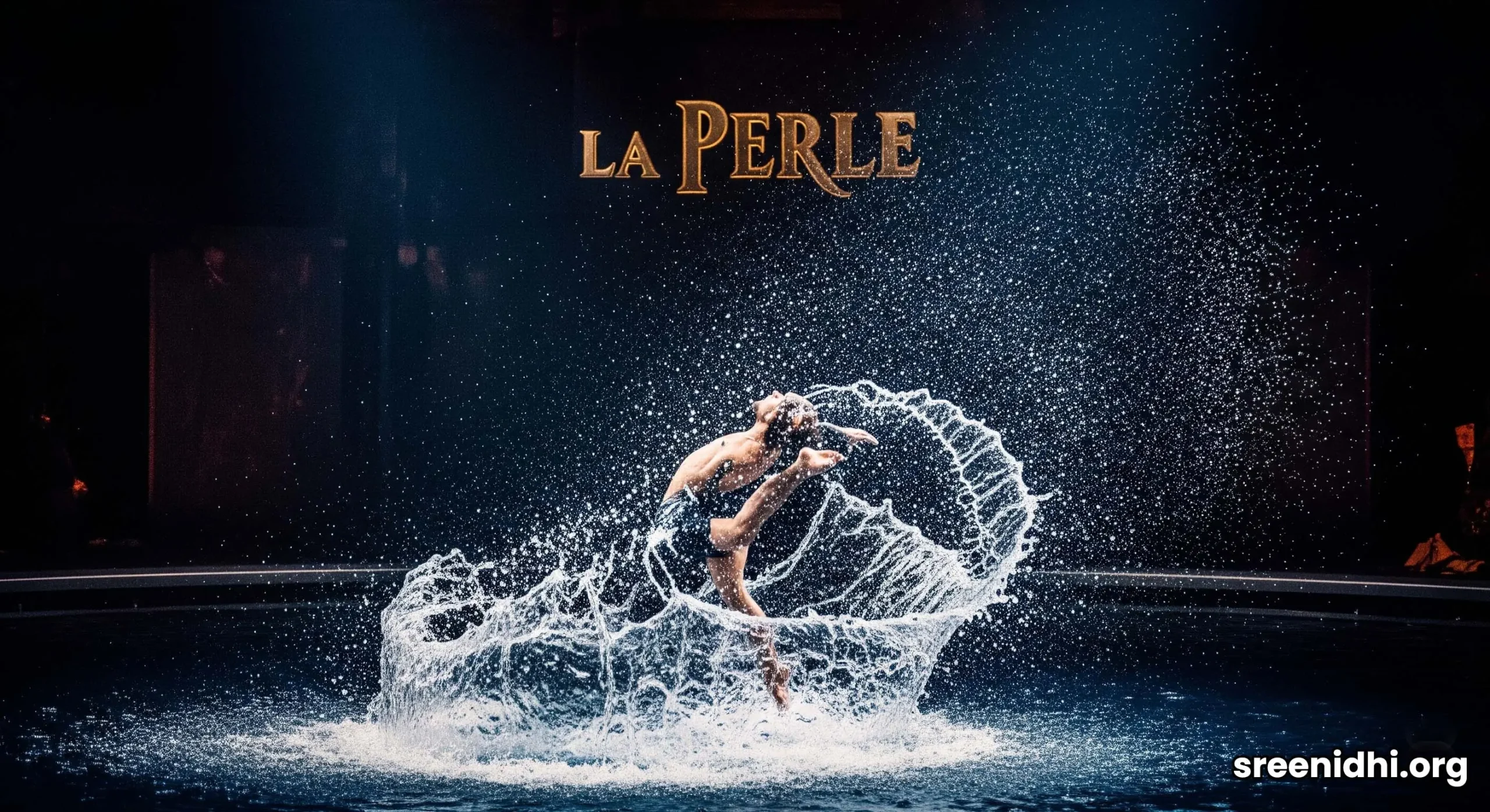 A dramatic scene from the La Perle aqua-show in Dubai, with acrobats diving into a glowing blue stage pool.