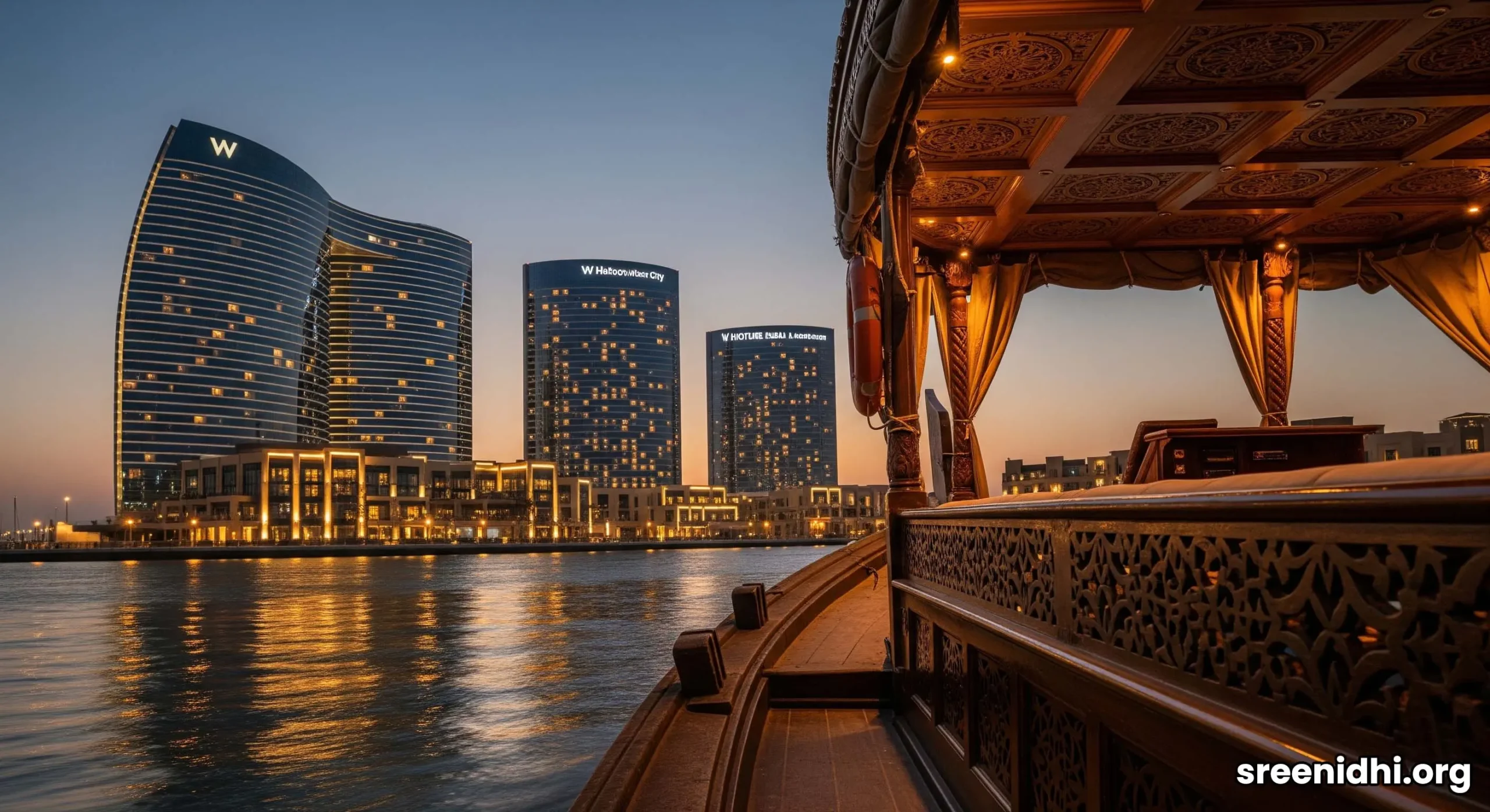 The three illuminated towers of Al Habtoor City at twilight, reflecting in the calm waters of the Dubai Water Canal.